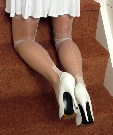 Clothed brunette Taya displays her shapely legs in nylons and white heels 70885463