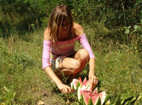Young girl carves up a watermelon while outdoors before eating it in the nude 97226081