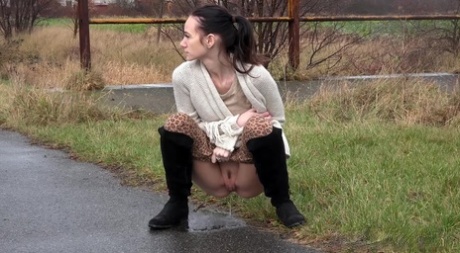 Short taken girl Eveline Neill pees on a paved path on a wet and dreary day 60633640