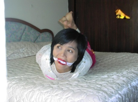 Asian girl is cleaved gagged while tied up in her clothing on a bed 50406106