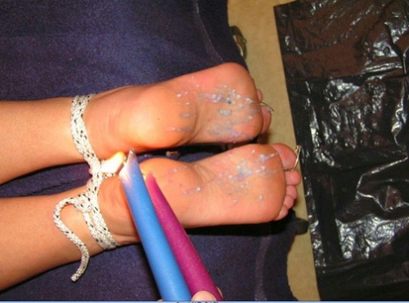 Caucasian female has the soles of her feet covered in hot candle wax 97385365