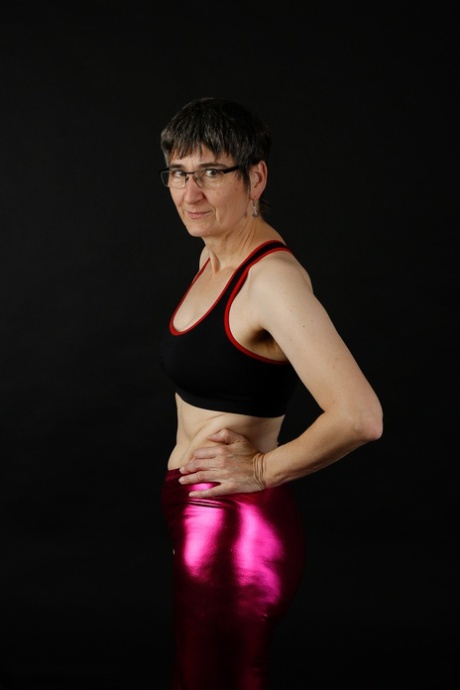 Mature woman models a sports bra in shiny pants and black boots 96188143