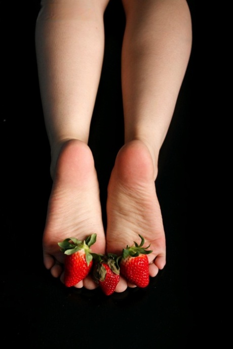 Caucasian female adorns her naked feet with strawberries 70320846